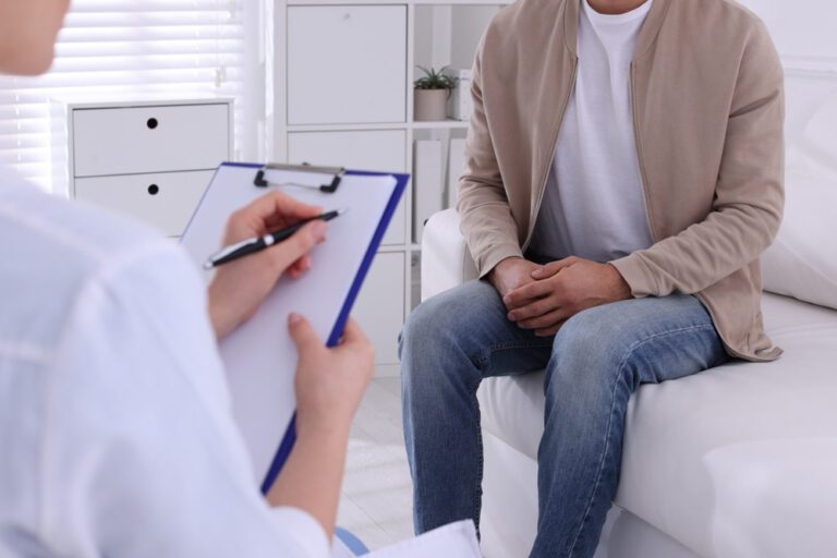 Homem sentado em sofá participando de uma consulta com médico.